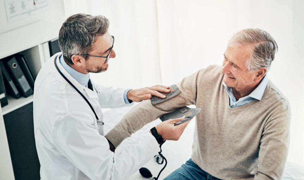 Image of a man checking his blood pressure for hypertension with the help of his doctor.